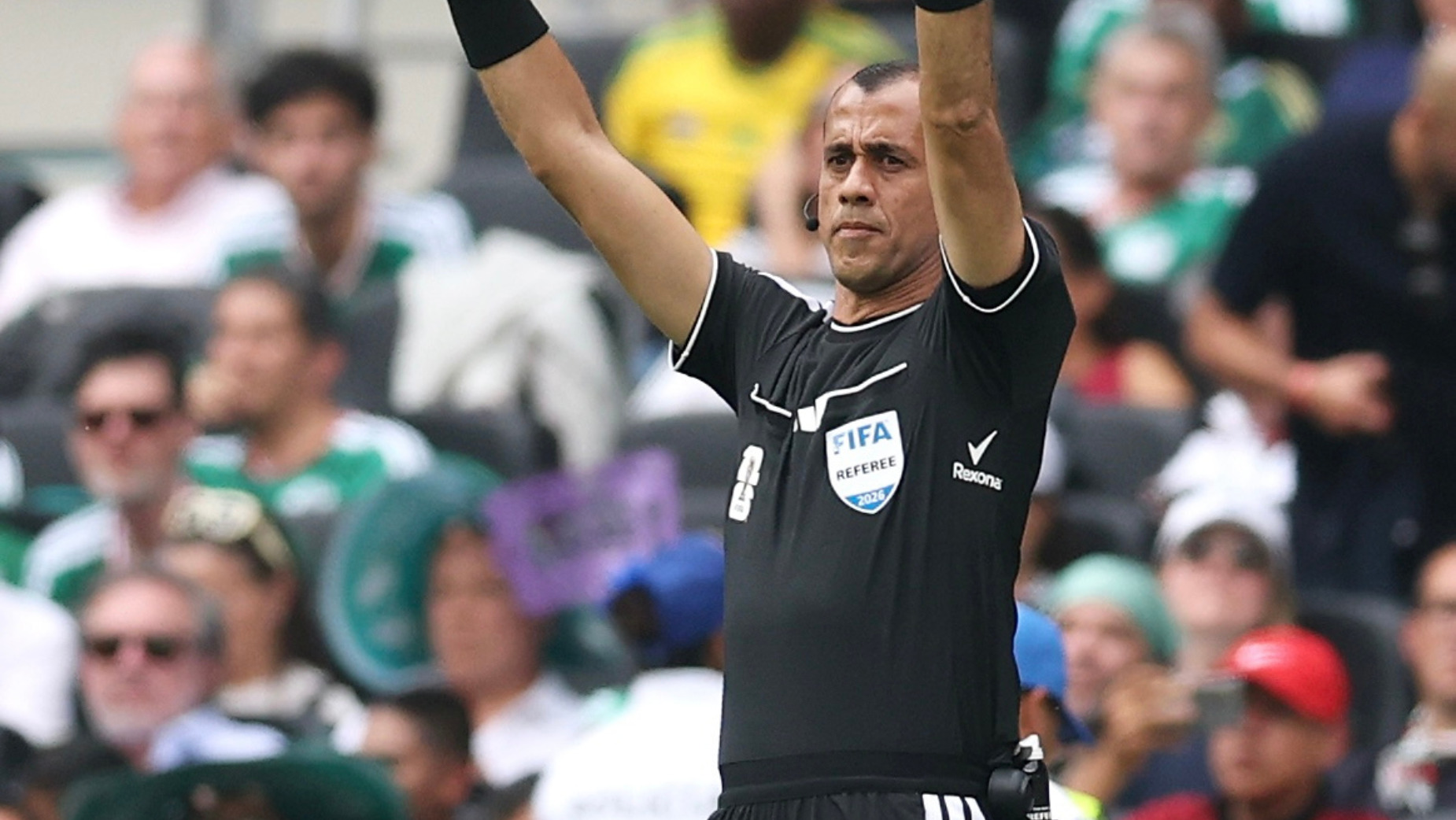 A FIFA World Cup 2026 referee raising both arms, with the Rexona logo visible near the underarm of the uniform